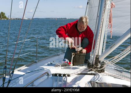 Angler an Bord einer Segelyacht entfernt einen frisch gefangenen Hecht Stockfoto