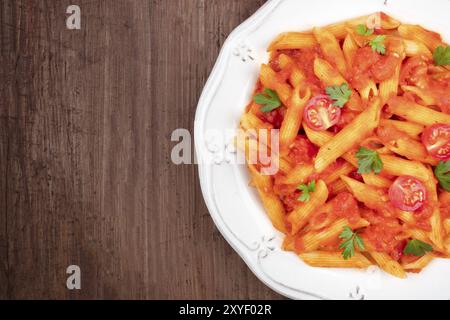 Eine Nahaufnahme von Penne Nudeln mit Tomatensoße, Schuß von oben auf einen dunklen Holzmöbeln im Landhausstil Hintergrund mit einem Platz für Text Stockfoto