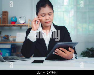 Geschäftsfrau arbeitet mit Stress, weil sie sehr müde ist, mit Laptop und Dokumenten auf dem Tisch zu arbeiten, Frau schläfrig und gelangweilt von der Arbeit, sitzt Stockfoto