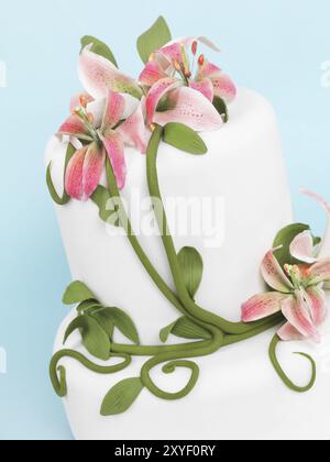 Torte, dekoriert mit Lilien auf blauem Hintergrund isoliert Stockfoto