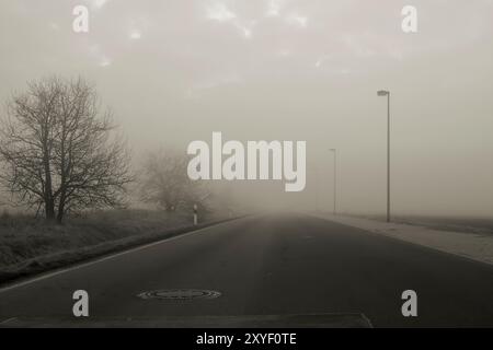 Einsame Landstraße im Nebel bei Sonnenaufgang Stockfoto