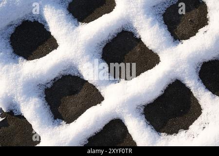 Schnee an den Fugen von Pflastersteinen auf einem Fußgängerweg im Winter Stockfoto