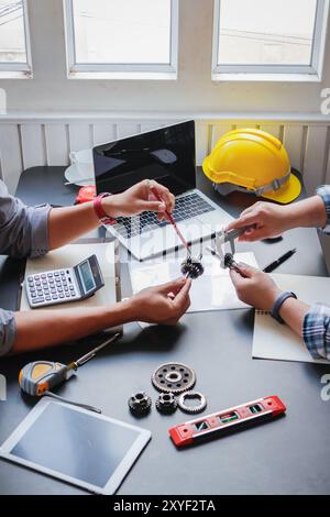 Die Ausrüstung und Dokumente des Technikteams auf den Schreibtischen im Büro sowie die gelben Helme, die beim Betreten der Baustelle getragen werden können Stockfoto