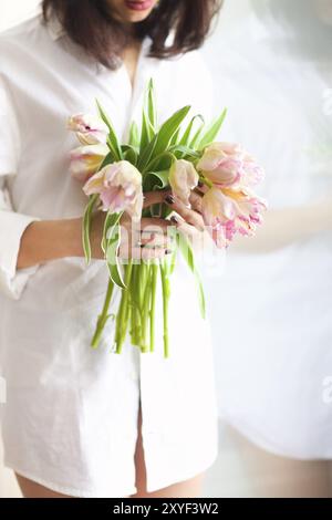 Schöne junge Frau hält eine Reihe von zarten Frühling rosa Tulpen vor ihr. Nahaufnahme Stockfoto