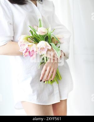 Schöne junge Frau hält eine Reihe von zarten Frühling rosa Tulpen vor ihr. Nahaufnahme Stockfoto