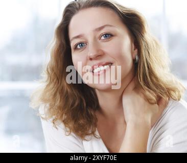 Porträt von glücklich lächelnden blonden Frau am Fenster Stockfoto