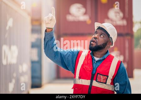 Porträt eines afrikanischen Ingenieurs oder Vorarbeiters trägt PSA, die die Containerlagerung mit Hintergrund des Frachtbehälters bei Sonnenuntergang überprüft. Logistik Global Import oder Exp Stockfoto