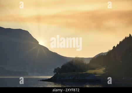 Fjord mit Blick auf Berge und Fjordlandschaft in Norwegen. Die Sonne geht hinter dem Berg unter. Landschaftsaufnahmen aus dem Norden Skandinaviens Stockfoto