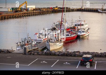 HUSAVIK, ISLAND, 29. JUNI: Ruhiger Hafen mit verankertem Fischerboot und Bergen im Hintergrund am 29. Juni 2013 in Husavik, Island, Europa Stockfoto