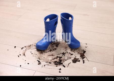 Gummistiefel mit Schlamm auf Holzboden Stockfoto