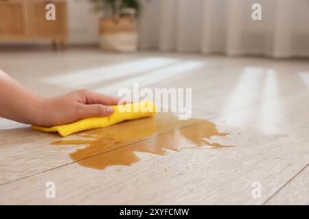 Frau wischt die Pfütze von verschüttetem Getränk auf dem Boden ab, Nahaufnahme Stockfoto
