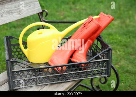 Orangefarbene Gummistiefel und Gartenwerkzeuge in Kisten im Freien Stockfoto