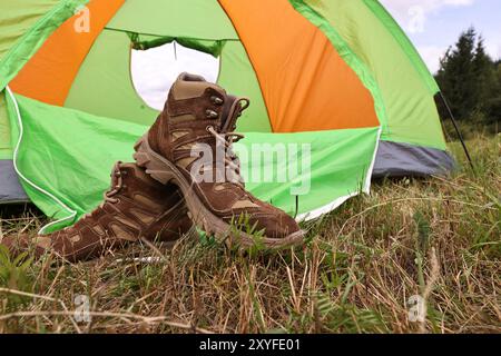 Wanderschuhe und Campingzelt auf grünem Gras im Freien Stockfoto