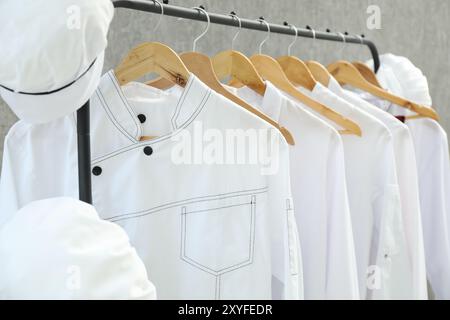 Uniformen der Köche auf Kleiderständer vor grauem Hintergrund, Nahaufnahme Stockfoto