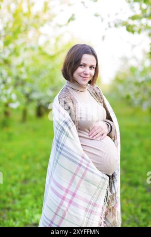 Glücklich schöne schwangere Frau im blühenden Garten Stockfoto