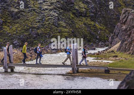 LANDMANNALAUGAR, ISLAND, 09. JULI: Einige Touristen überqueren am 09. Juli 2013 einen Fluss auf einer Holzstege in Landmannalaugar, Island, Europa Stockfoto