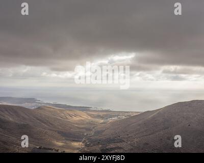 Panoramablick auf hügeliges Gelände mit bewölktem Himmel und Lichtstrahlen, die durch Wolken brechen, lanzarote, Kanarische Inseln, Spanien, Europa Stockfoto