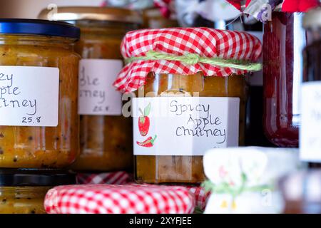 Uk. Hausgemachtes würziges Apfelchutney in Glasgläsern, beschriftet und mit einer Stoffauflage versehen. Hergestellt mit saisonalen hausgemachten Äpfeln Stockfoto