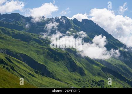 Ein Sommertag in Savoyen mit einem grünen, grasbewachsenen Berg mit verstreuten Wolken, ein idealer Trekkingort mit malerischem Blick auf die Landschaft, Alpen in Frankreich Stockfoto