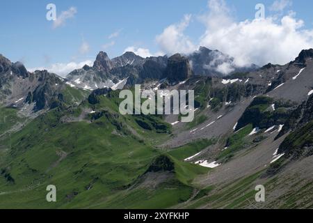 Berglandschaft von Pierra Menta Mont in Beaufort, Savoie, Frankreich, mit üppigem grünem Gras und Wolken, die im Sommer über die Gipfel treiben Stockfoto