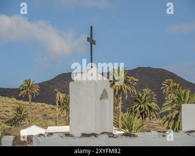 Kirche mit einem Kreuz auf der Spitze und Palmen im Hintergrund unter bewölktem Himmel, lanzarote, Kanarische Inseln, Spanien, Europa Stockfoto