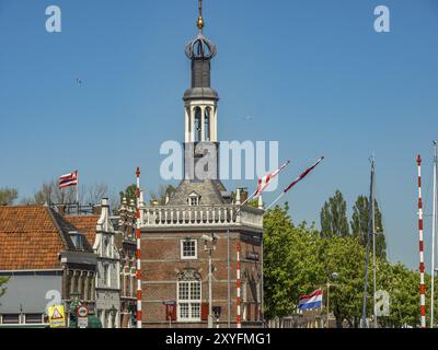 Alter Turm mit Fahnen vor einem Kanal und historische Gebäude an einem klaren Sommertag, alkmaar, niederlande Stockfoto