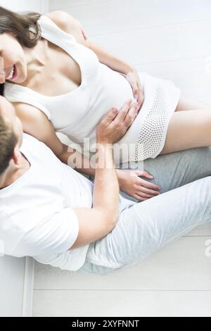 Draufsicht der junge Mann und ziemlich schwanger Frau umarmt zusammen drinnen Stockfoto