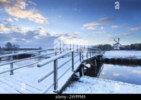 Brücke über den Fluss zur Windmühle im Winter, Holland Stockfoto