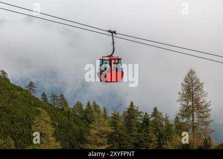 Rote Seilbahnkabine über den Bäumen auf einem Hügel im Nebel, Katrinbahn Bad Ischl, Österreich Stockfoto