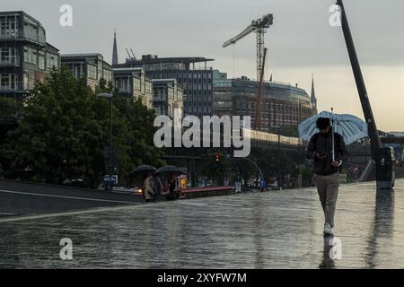 Symbolisches Bildwetter, starker Regen im Sommer, Gewitter, Sturm, Tourist mit Schirm unterwegs im Regen neben der U-Bahn-Linie U3 bei t Stockfoto
