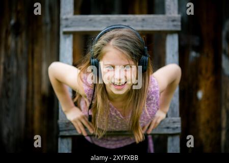 Ein verspieltes Porträt eines Teenagers mit Kopfhörern und einem schelmischen Lächeln. Stockfoto