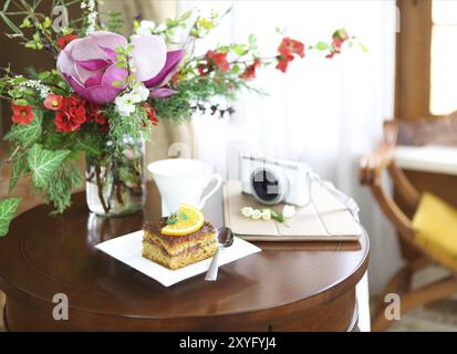 Schokolade Kuchen, Tee, Tablet-PC, Kamera und Blumenstrauß der Blüte Frühling Blumen auf dem Tisch. Stall leben Stockfoto