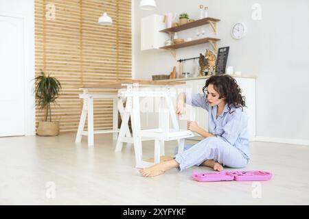 Frau, die sich in die neue Wohnung Haus Zusammenbau von Möbeln mit Schraubendreher. Junge Mädchen, die die inneren. Frau und die Bengal Katze auf die Küche Stockfoto