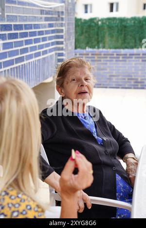 Alte Mutter, die mit ihrer Tochter auf einer Terrasse in die Kamera schaut Stockfoto