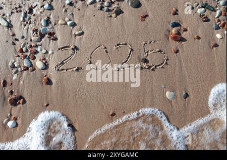 Nachricht Jahr 2024 ersetzt durch 2025 Text auf Strand Sand Hintergrund geschrieben. Auf Wiedersehen 2024 Hallo zu 2025 Happy New Year Coming Concept. Draufsicht. Estland Stockfoto