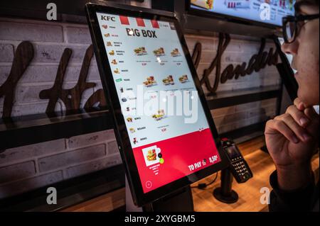 Wien, Österreich, 23. August 2022. Aufnahme der Anzeige für die unabhängige Auftragserteilung in einem kfc-Geschäft. Der Junge starrt auf den Bildschirm und denkt nach, welche Wahl es gibt Stockfoto