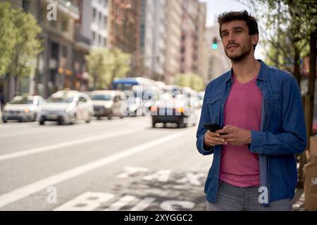 Mann wartet auf einen Bus, männlicher Tourist reist durch die Stadt, Mann, der sein Smartphone benutzt, um ein Taxi zu nehmen. Stockfoto