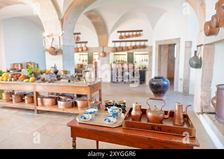 SINTRA, Portugal – die große Küche im Pena Palace mit einer beeindruckenden Auswahl an Kupferkochtöpfen und Kochmöglichkeiten aus dem 19. Jahrhundert. Dieser gut erhaltene Raum bietet Besuchern einen Einblick in die kulinarischen Aktivitäten eines königlichen Haushalts mit seinem weitläufigen Herd, den kunstvollen Fliesen und den glänzenden Utensilien, die den opulenten Charakter des Palastes und die fortschrittlichen Kochtechnologien der Zeit widerspiegeln. Stockfoto