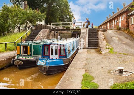 Schmalboote, die durch die Doppeltreppenschleusen auf dem Shropshire Union Kanal bei Bunbury Cheshire fahren, mit Blick auf die historischen denkmalgeschützten Ställe Stockfoto