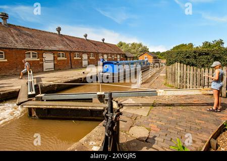 Schmalboot, das durch die Doppeltreppenschleusen auf dem Shropshire Union Kanal bei Bunbury Cheshire fährt, mit Blick auf die historischen denkmalgeschützten Ställe Stockfoto