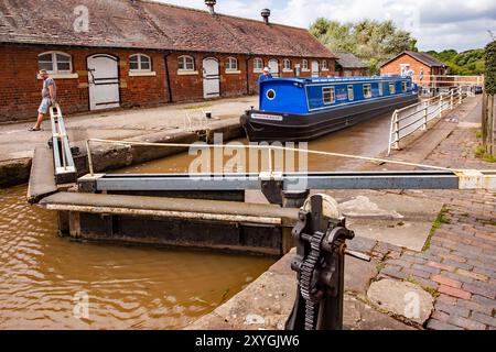 Schmalboot, das durch die Doppeltreppenschleusen auf dem Shropshire Union Kanal bei Bunbury Cheshire fährt, mit Blick auf die historischen denkmalgeschützten Ställe Stockfoto