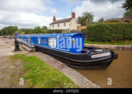 Schmalboot, das durch die Doppeltreppenschleusen auf dem Shropshire Union Kanal bei Bunbury Cheshire fährt, mit Blick auf das Schleusenhäuschen Stockfoto