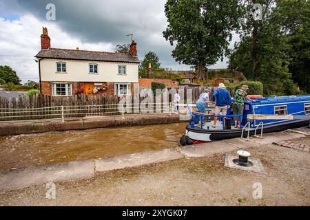 Schmalboot, das durch die Doppeltreppenschleusen auf dem Shropshire Union Kanal bei Bunbury Cheshire fährt, mit Blick auf das Schleusenhäuschen Stockfoto