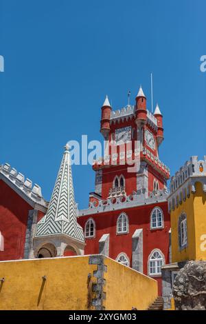 SINTRA, Portugal – der prunkvolle rote Turmglockenturm des Pena Palace hebt sich vom Himmel ab und zeigt die lebhaften Farben und die eklektische romantische Architektur dieser königlichen Residenz aus dem 19. Jahrhundert. Diese Besonderheit verkörpert den märchenhaften Charme, der Pena Palace zu einem Wahrzeichen in Sintra macht. Stockfoto