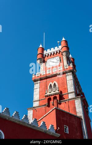 SINTRA, Portugal – der prunkvolle rote Turmglockenturm des Pena Palace hebt sich vom Himmel ab und zeigt die lebhaften Farben und die eklektische romantische Architektur dieser königlichen Residenz aus dem 19. Jahrhundert. Diese Besonderheit verkörpert den märchenhaften Charme, der Pena Palace zu einem Wahrzeichen in Sintra macht. Stockfoto