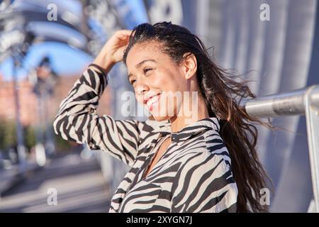 Junge Latina mit langen, brünetten Haaren, die lächeln und ihre weißen Zähne zeigen Stockfoto