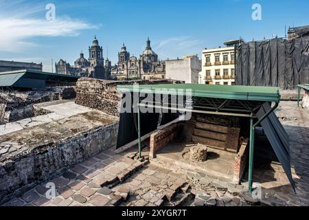 MEXIKO-STADT, Mexiko – die Metropolitano Sagrario und Catedral Metropolitana in der Ferne, von den ausgegrabenen Ruinen des Bürgermeisters von Templo aus gesehen. Diese eindrucksvolle Gegenüberstellung zeigt die geschichtsträchtige Geschichte von Mexiko City, mit katholischen Strukturen aus der Kolonialzeit, die über den Überresten des Haupttempels des Aztekenreichs ragen. Stockfoto