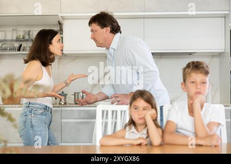 Eltern streiten sich hinter dem Rücken von verschwommenem, unerkennbarem Sohn und Tochter. Stockfoto