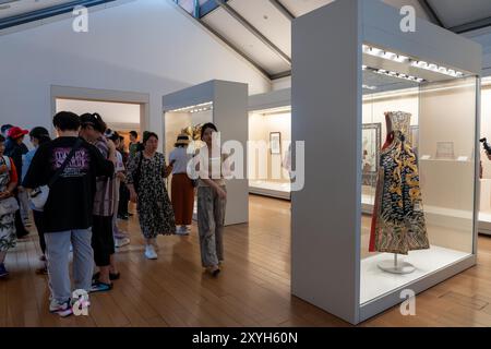 Suzhou, China - 12. Juni 2024 : Eine Gruppe von Menschen spaziert durch eine Museumsgalerie in Suzhou, China, mit mehreren Glasvitrinen, die Artefakte zeigen Stockfoto