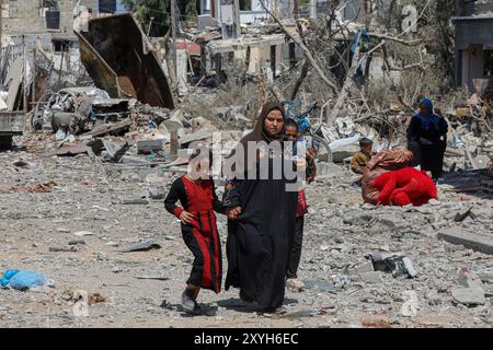 Gaza. August 2024. Vertriebene kehren am 29. August 2024 in der Stadt Deir al-Balah im zentralen Gazastreifen zurück. Am Donnerstag sagte das UN-Büro für die Koordinierung humanitärer Angelegenheiten (OCHA), dass die israelischen Behörden angekündigt haben, dass Vertriebene in bestimmte Gebiete in Deir al-Balah zurückkehren könnten, das erste Mal, dass die Rückkehr in ein evakuiertes Gebiet offiziell erlaubt ist. Quelle: Rizek Abdeljawad/Xinhua/Alamy Live News Stockfoto